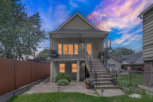 9620 S Exchange Ave, Chicago, IL 60617 - back of property at dusk featuring stairway, a fenced backyard, and a porch