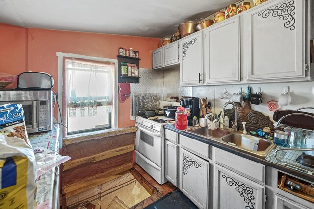 9620 S Exchange Ave, Chicago, IL 60617 - kitchen featuring white range with gas cooktop, stainless steel microwave, a sink, white cabinetry, and dark countertops