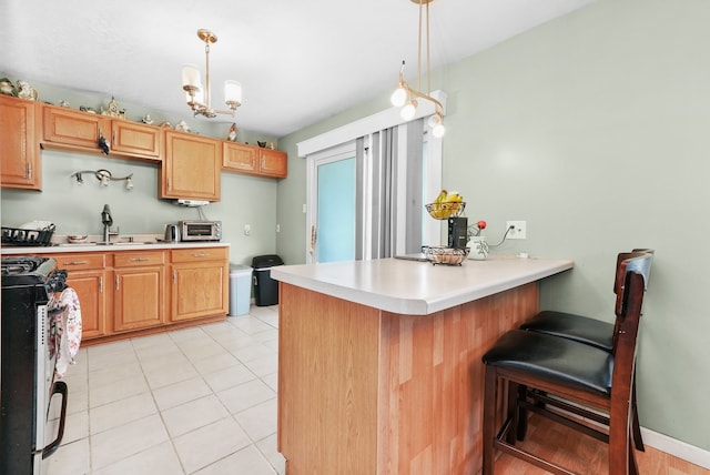 136 Anita Dr, Bourbonnais, IL 60914 - kitchen featuring range with gas cooktop, a peninsula, light countertops, and a breakfast bar