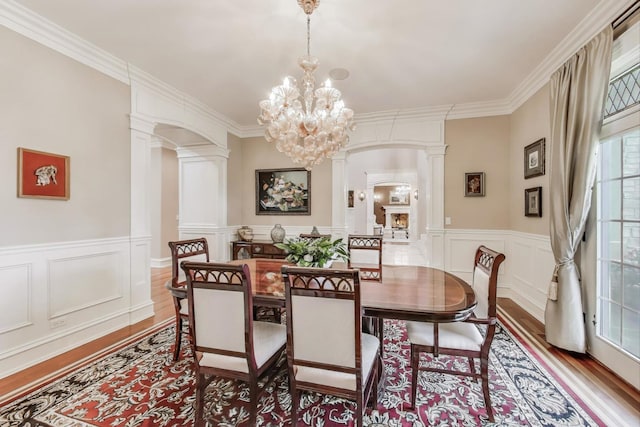 724 Becker Rd, Glenview, IL 60025 - dining space featuring wood finished floors, arched walkways, ornate columns, a chandelier, and ornamental molding