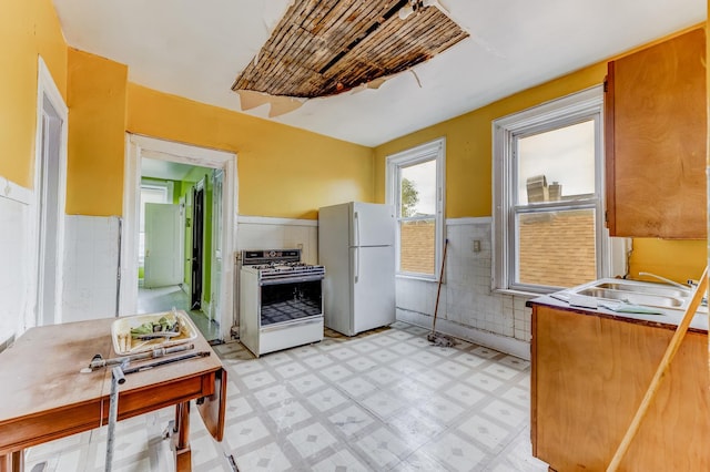 2227 W 21st St, Chicago, IL 60608 - kitchen with white appliances, light flooring, wainscoting, a sink, and tile walls
