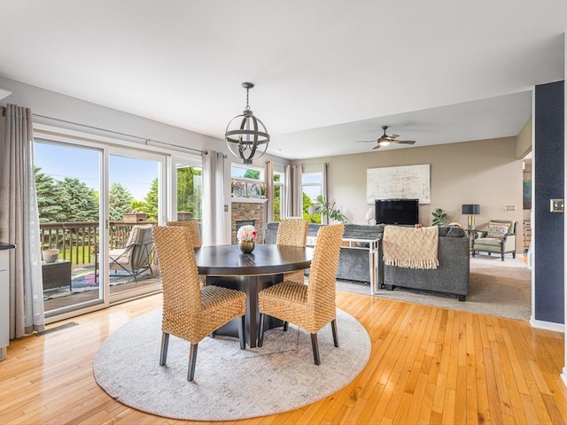 11546 Ridgecrest Dr, Roscoe, IL 61073 - dining space featuring a fireplace, ceiling fan, light wood-style flooring, and a chandelier