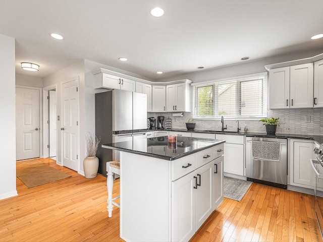 11546 Ridgecrest Dr, Roscoe, IL 61073 - kitchen featuring stainless steel dishwasher, freestanding refrigerator, light wood-style floors, decorative backsplash, and a breakfast bar