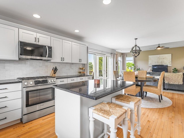 11546 Ridgecrest Dr, Roscoe, IL 61073 - kitchen featuring appliances with stainless steel finishes, open floor plan, light wood-style floors, decorative backsplash, and a kitchen breakfast bar