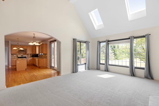 7N001 Ridge Line Rd, Saint Charles, IL 60175 - unfurnished living room with arched walkways, a chandelier, high vaulted ceiling, light carpet, and a skylight
