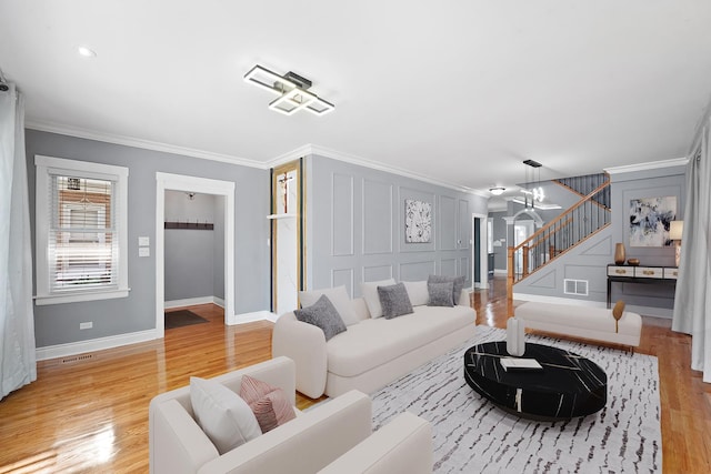 5151 W Fletcher St, Chicago, IL 60641 - living room featuring stairs, crown molding, light wood-style flooring, baseboards, and a decorative wall