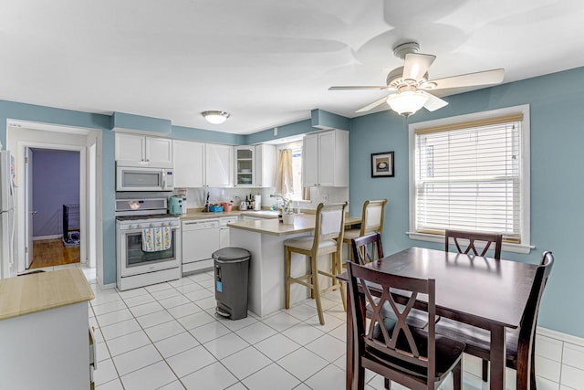 4730 N Hermitage Ave Unit 2F, Chicago, IL 60640 - kitchen featuring white appliances, a ceiling fan, light countertops, a peninsula, and white cabinetry