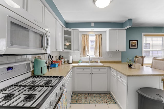 4730 N Hermitage Ave Unit 2F, Chicago, IL 60640 - kitchen with a sink, white range with gas stovetop, a peninsula, tasteful backsplash, and white cabinetry