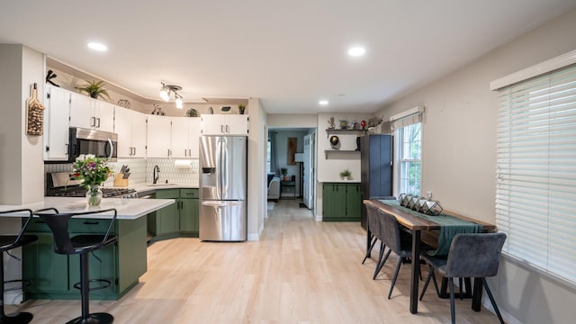 55 S Elmwood Ave, Palatine, IL 60074 - kitchen with stainless steel appliances, a sink, green cabinets, a peninsula, and light countertops