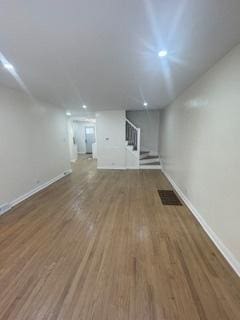 9536 S Woodlawn Ave, Chicago, IL 60628 - unfurnished living room with stairs, baseboards, wood finished floors, and recessed lighting