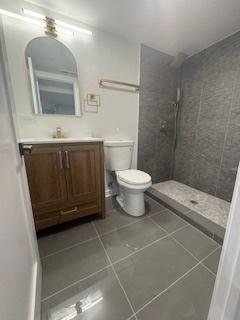 9536 S Woodlawn Ave, Chicago, IL 60628 - full bathroom with vanity, a tile shower, tile patterned flooring, and toilet