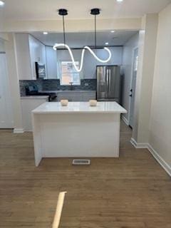 9536 S Woodlawn Ave, Chicago, IL 60628 - kitchen featuring stainless steel refrigerator with ice dispenser, baseboards, white cabinetry, a center island, and decorative backsplash