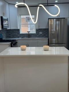 9536 S Woodlawn Ave, Chicago, IL 60628 - kitchen featuring stainless steel refrigerator with ice dispenser, range, backsplash, a chandelier, and light countertops