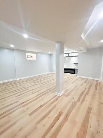 9536 S Woodlawn Ave, Chicago, IL 60628 - finished below grade area with baseboards, light wood-style floors, and a fireplace