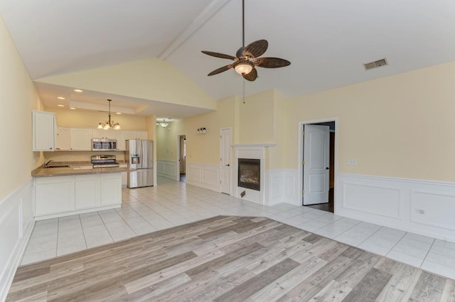 262 Jennifer Ln Unit 262, Wilmington, IL 60481 - kitchen with stainless steel appliances, a sink, open floor plan, a decorative wall, and beamed ceiling