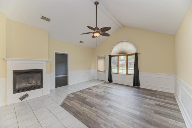 262 Jennifer Ln Unit 262, Wilmington, IL 60481 - unfurnished living room featuring a ceiling fan, a decorative wall, a glass covered fireplace, wainscoting, and light wood-type flooring