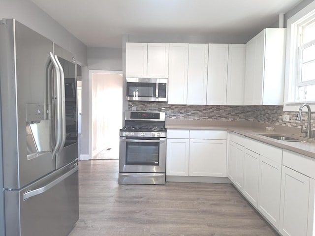8732 S Laflin St, Chicago, IL 60620 - kitchen with stainless steel appliances, a sink, white cabinets, decorative backsplash, and light countertops