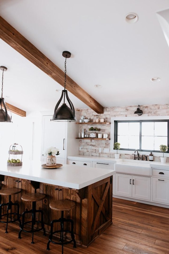 281 Snipe Hollow Rd N, Elizabeth, IL 61028 - kitchen featuring white cabinets, beamed ceiling, light countertops, pendant lighting, and a breakfast bar