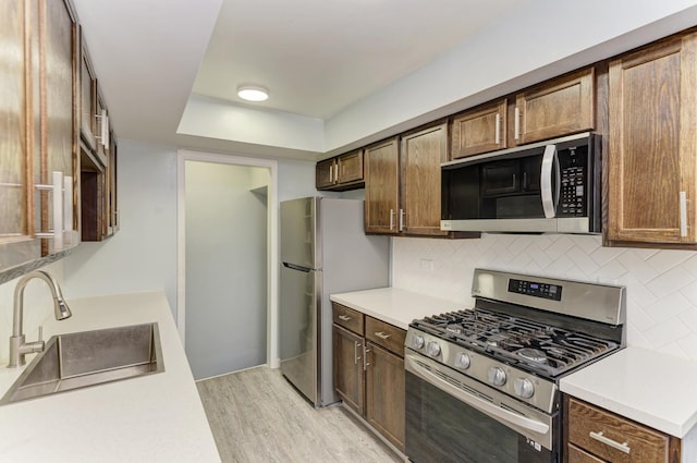7 Fernwood Dr Unit Q, Bolingbrook, IL 60440 - kitchen with appliances with stainless steel finishes, a sink, light wood-type flooring, decorative backsplash, and light countertops