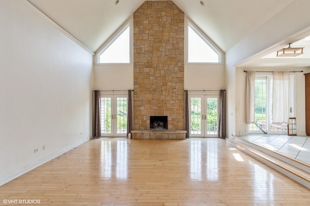 4722 Douglas Rd, Oswego, IL 60543 - unfurnished living room featuring french doors, high vaulted ceiling, a stone fireplace, light wood-style floors, and baseboards