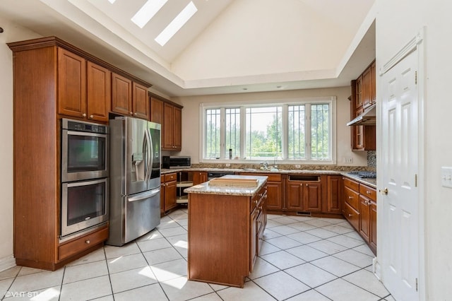 4722 Douglas Rd, Oswego, IL 60543 - kitchen with appliances with stainless steel finishes, under cabinet range hood, a center island, brown cabinets, and a skylight