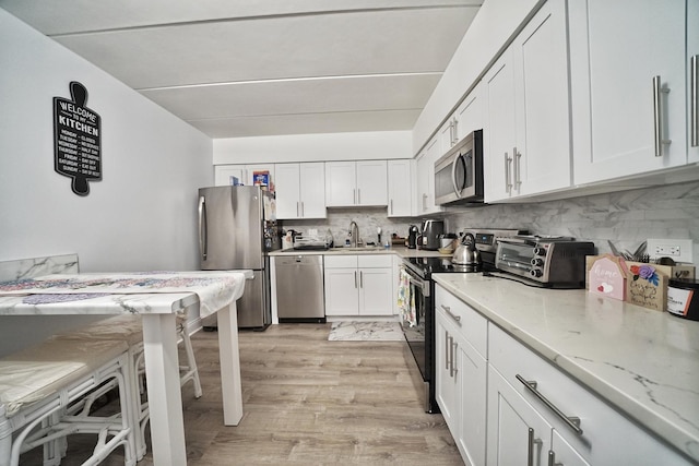 603 S River Rd Unit 2K, Des Plaines, IL 60016 - kitchen with appliances with stainless steel finishes, a sink, backsplash, white cabinetry, and light stone countertops