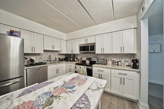603 S River Rd Unit 2K, Des Plaines, IL 60016 - kitchen with stainless steel appliances, a sink, tasteful backsplash, and white cabinets