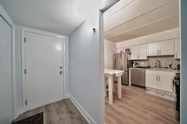 603 S River Rd Unit 2K, Des Plaines, IL 60016 - kitchen with stainless steel appliances, light wood-style flooring, a sink, white cabinetry, and tasteful backsplash