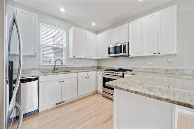2847 N Wolcott Ave Unit D, Chicago, IL 60657 - kitchen with stainless steel appliances, a sink, light wood-style floors, white cabinetry, and light stone counters