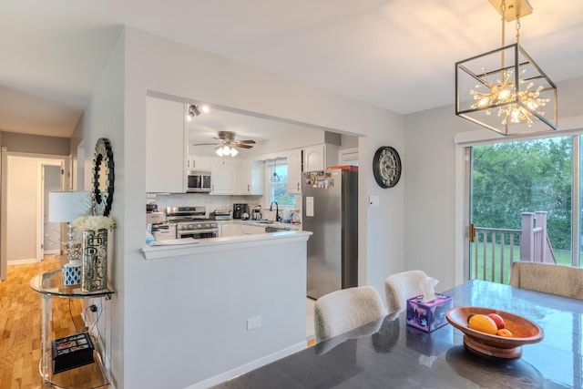 8106 W 89th Pl, Hickory Hills, IL 60457 - kitchen with stainless steel appliances, a sink, white cabinetry, a peninsula, and a chandelier