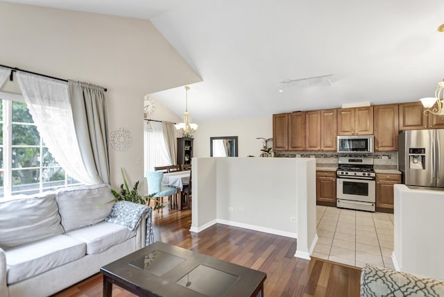 2439 Daybreak Ct Unit 2439, Elgin, IL 60123 - living room featuring a chandelier, track lighting, lofted ceiling, and light wood-style flooring