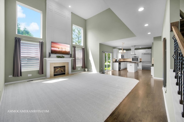 351 Tiger St, Bolingbrook, IL 60490 - unfurnished living room featuring a towering ceiling, a tiled fireplace, baseboards, recessed lighting, and dark wood finished floors