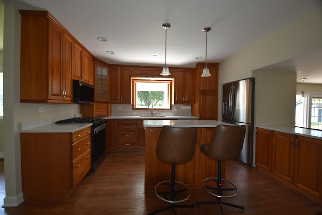 kitchen featuring stainless steel appliances, brown cabinetry, healthy amount of natural light, a kitchen breakfast bar, and recessed lighting