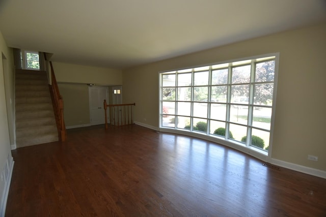 unfurnished living room featuring dark wood-style floors and stairway