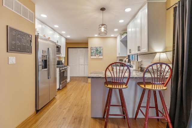 67 Alice St, Algonquin, IL 60102 - kitchen featuring stainless steel appliances, white cabinets, a peninsula, light wood-type flooring, and recessed lighting