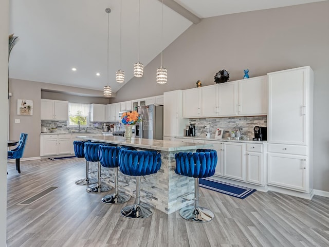 1811 Cumberland Dr, Plainfield, IL 60586 - kitchen featuring stainless steel refrigerator with ice dispenser, a sink, a breakfast bar area, light wood-type flooring, and high vaulted ceiling
