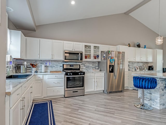 1811 Cumberland Dr, Plainfield, IL 60586 - kitchen featuring appliances with stainless steel finishes, high vaulted ceiling, a sink, white cabinets, and backsplash
