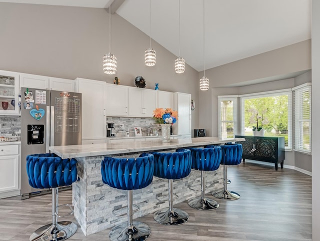 1811 Cumberland Dr, Plainfield, IL 60586 - kitchen with stainless steel fridge, high vaulted ceiling, light stone counters, light wood-style floors, and white cabinets