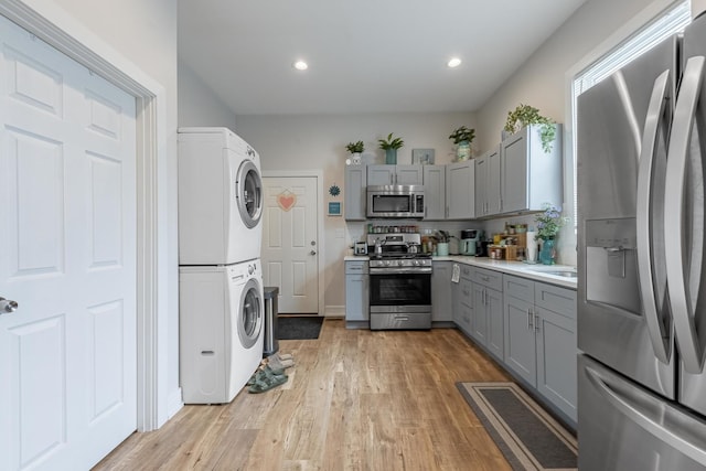 3331 S Ashland Ave, Chicago, IL 60608 - kitchen featuring appliances with stainless steel finishes, gray cabinets, stacked washer and clothes dryer, light wood finished floors, and recessed lighting