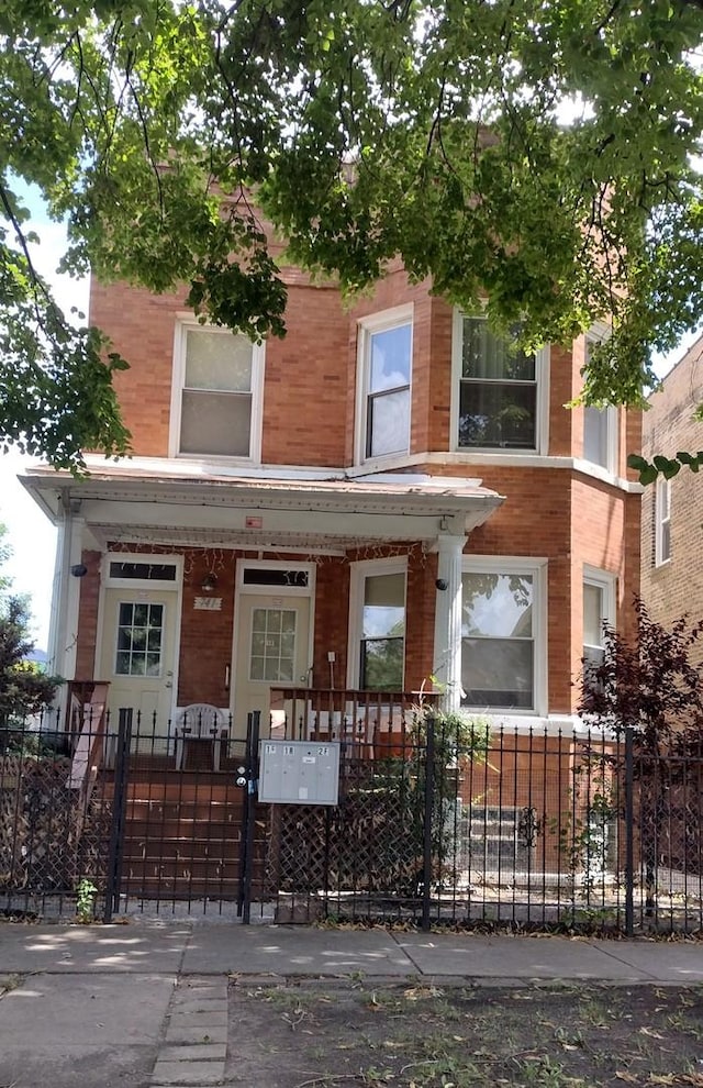 741 N Christiana Ave, Chicago, IL 60624 - view of front facade with a fenced front yard, brick siding, and covered porch