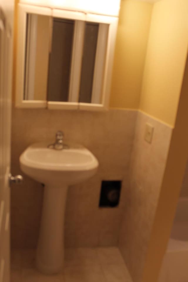 741 N Christiana Ave, Chicago, IL 60624 - bathroom featuring tile walls, a sink, and wainscoting