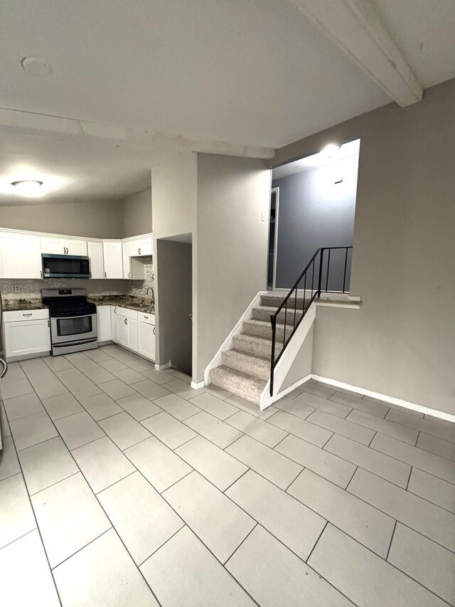 1403 Kings Rd, Carpentersville, IL 60110 - kitchen with appliances with stainless steel finishes, dark countertops, light tile patterned floors, and white cabinetry
