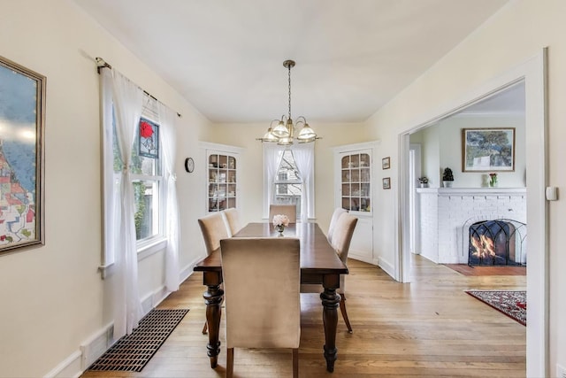 1314 Saint Johns Ave, Highland Park, IL 60035 - dining space with a chandelier, light wood finished floors, a fireplace, and baseboards