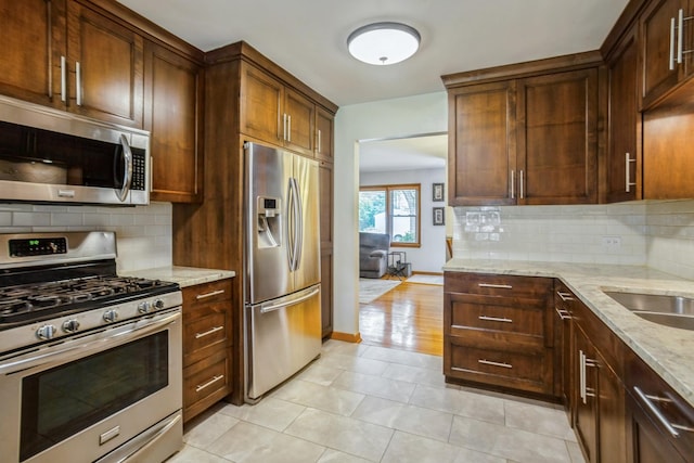430 Florian Dr, Des Plaines, IL 60016 - kitchen with stainless steel appliances, light stone counters, backsplash, and light tile patterned floors