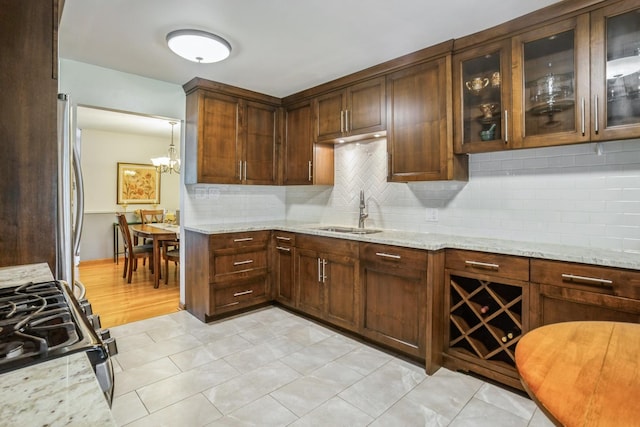 430 Florian Dr, Des Plaines, IL 60016 - kitchen with range with gas cooktop, tasteful backsplash, light stone countertops, glass insert cabinets, and light tile patterned floors