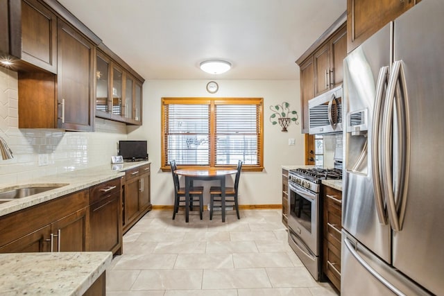 430 Florian Dr, Des Plaines, IL 60016 - kitchen featuring appliances with stainless steel finishes, backsplash, light stone counters, glass insert cabinets, and light tile patterned floors