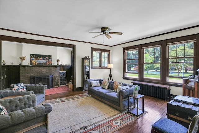 310 Davidson Dr, Champaign, IL 61821 - living room featuring radiator heating unit, wood finished floors, a ceiling fan, a brick fireplace, and crown molding