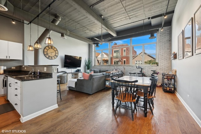 2750 N Wayne Ave Unit G, Chicago, IL 60614 - dining room with wood finished floors, track lighting, a towering ceiling, baseboards, and brick wall