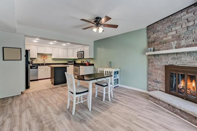 1640 Royal Oak Rd Unit 4, Darien, IL 60561 - dining room featuring a ceiling fan, a fireplace, light wood-style flooring, and baseboards