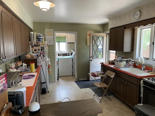 2068 David Dr, Des Plaines, IL 60018 - kitchen featuring washer and clothes dryer, light tile patterned floors, dark brown cabinetry, light countertops, and tile walls